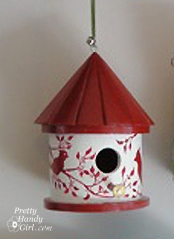 round white birdhouse with red roof and silhouette of birds and branches
