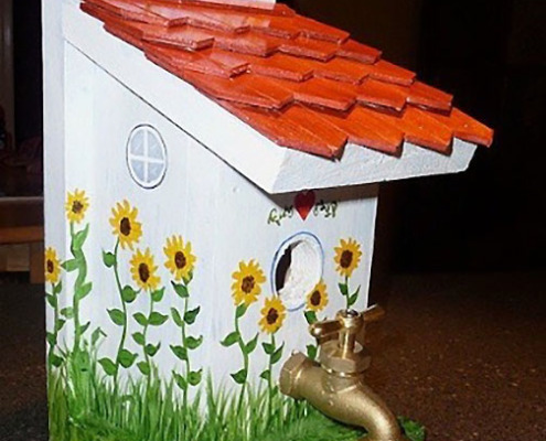 white birdhouse with red roof and spigot for perch
