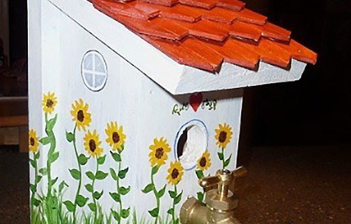 white birdhouse with red roof and spigot for perch