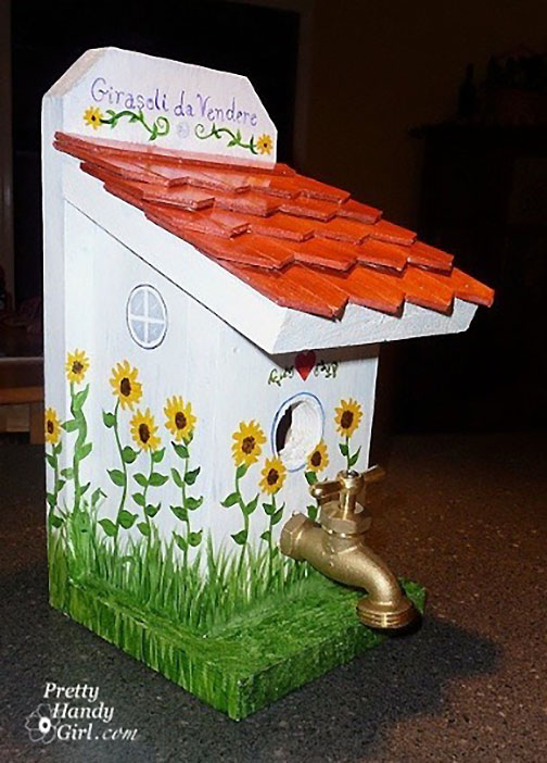 white birdhouse with red roof and spigot for perch