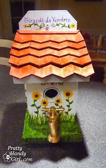 white birdhouse with red roof and spigot for perch