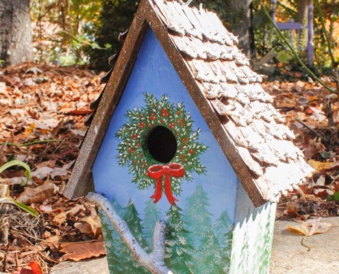 birdhouse with winter tree scene hand-painted, pine cone roof, and branch for perch