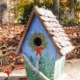 birdhouse with winter tree scene hand-painted, pine cone roof, and branch for perch