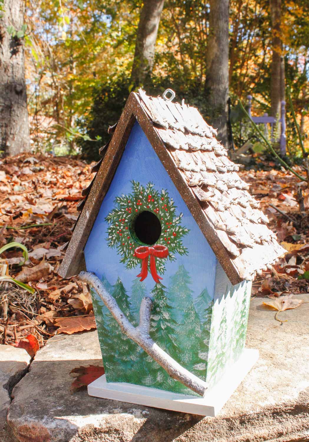 birdhouse with winter tree scene hand-painted, pine cone roof, and branch for perch