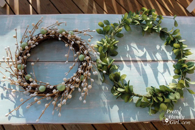 white berry wreath next to green leaf wreath