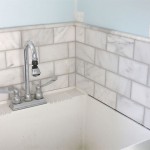 tiled and grouted marble subway tile backsplash around utility sink