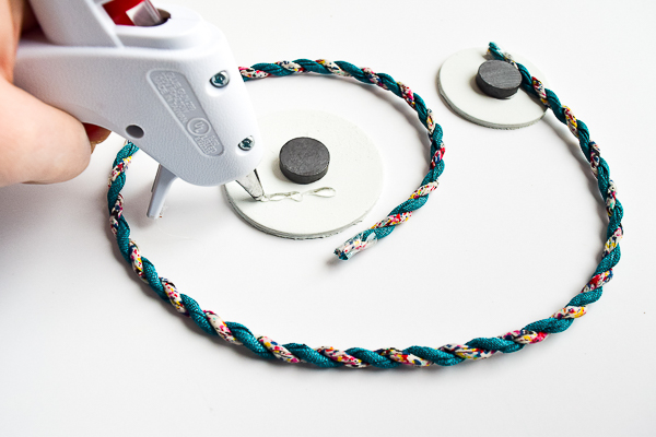 Attach each end of the ribbon or cord to the wooden shapes with hot glue.