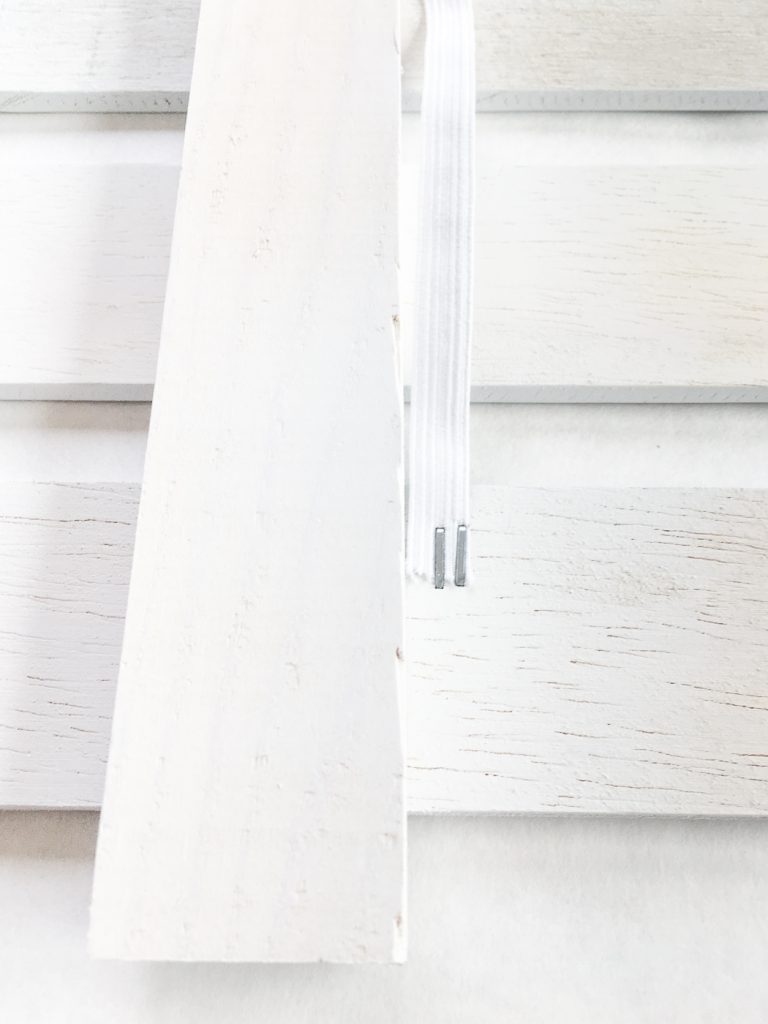 Staple the elastic to the back of the slat.