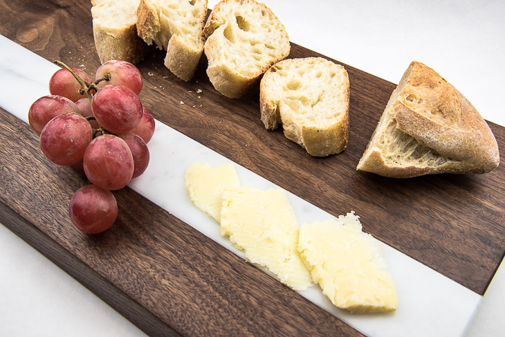This bread and cheese board is multi-functional! Cut bread on the wood section, and cheese on the marble! Pair with grapes for the perfect appetizer display!