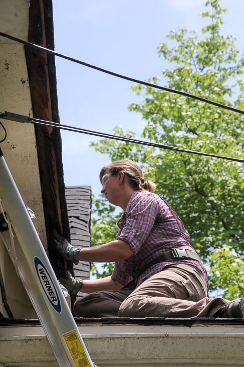 woman on porch roof removing soffit board