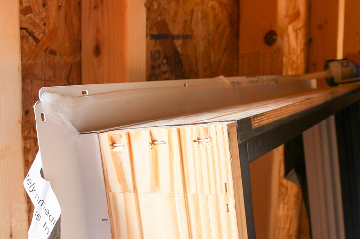 Add clear silicone caulk inside nailing flange of window.