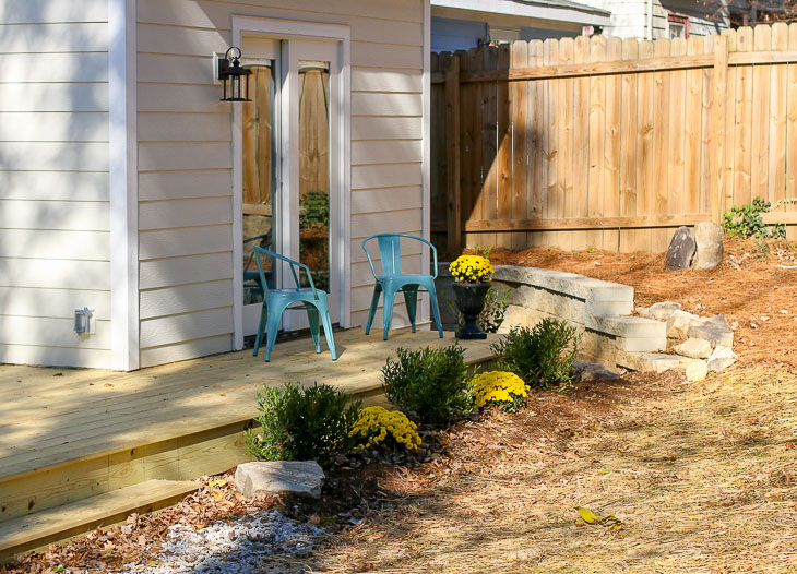back deck outside master bedroom with blue chairs and landscaping