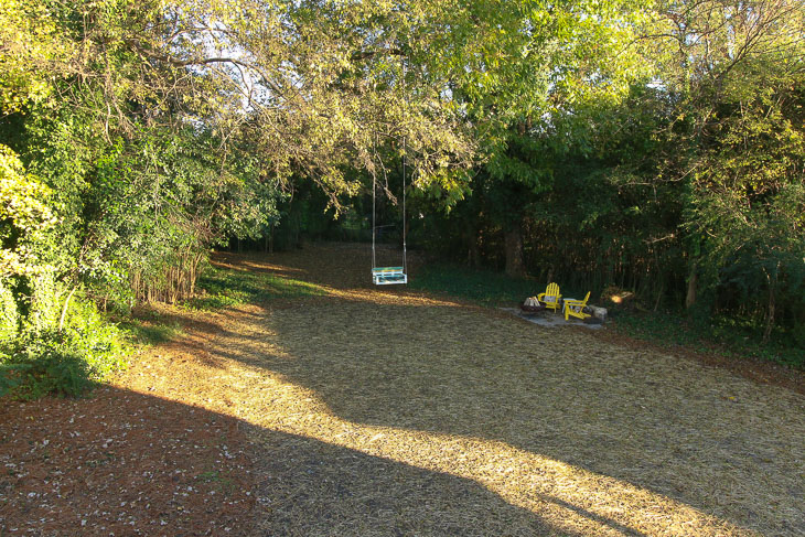 view from upstairs bedroom window of yard with tree swing and adirondack chairds