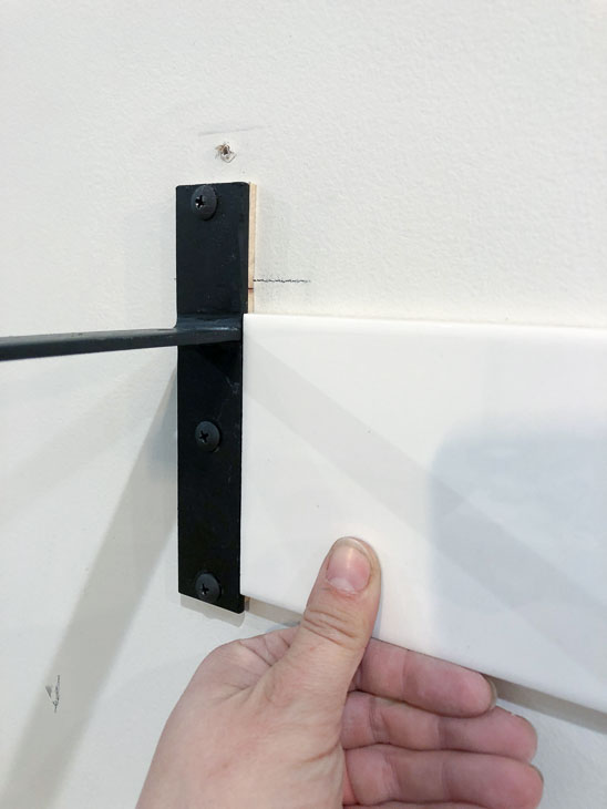 Subway tile next to shelf bracket