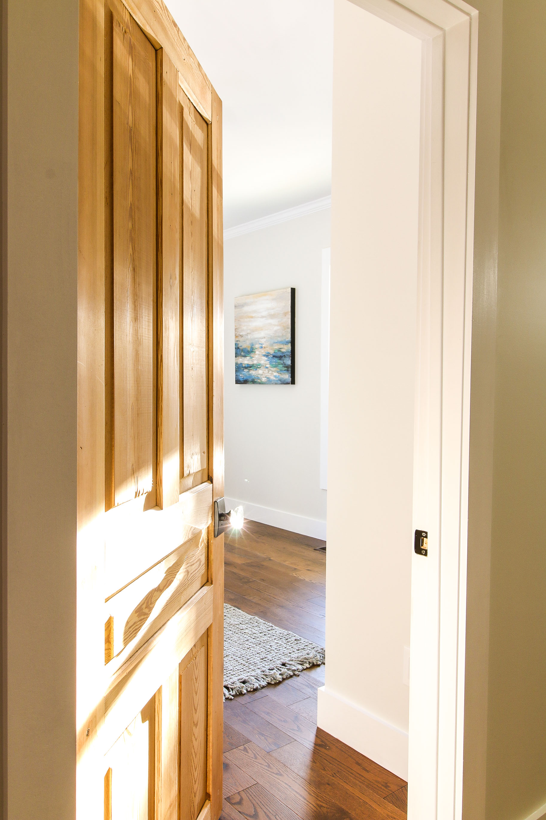 Door opening with ocean painting showing. Glass door knob with sun glinting on it.