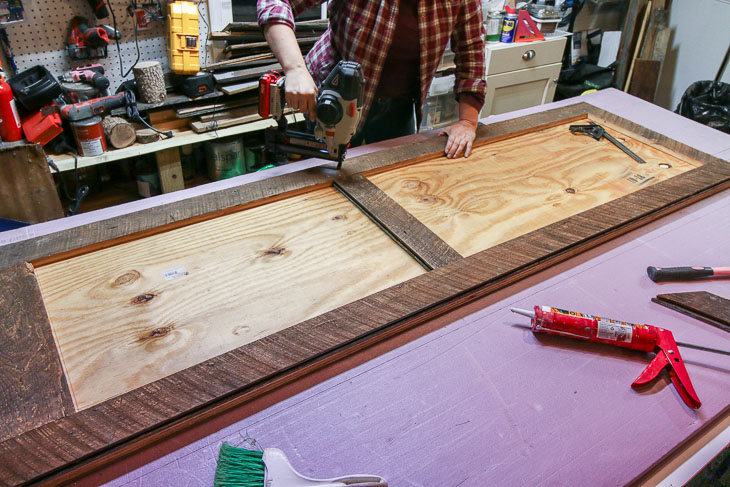 nail border pieces in place on reclaimed wood barn door