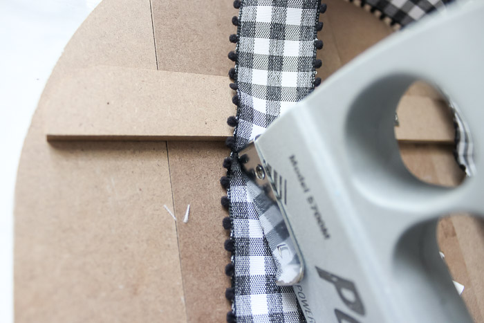 staple gun attaching ribbon to hang pumpkin sign
