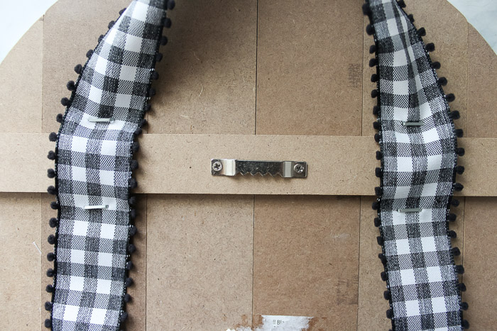 Overview of stapled on ribbon to the back of wooden pumpkin