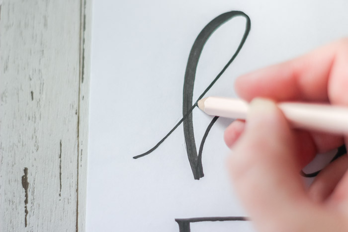 tracing over design with pencil to transfer onto pumpkin