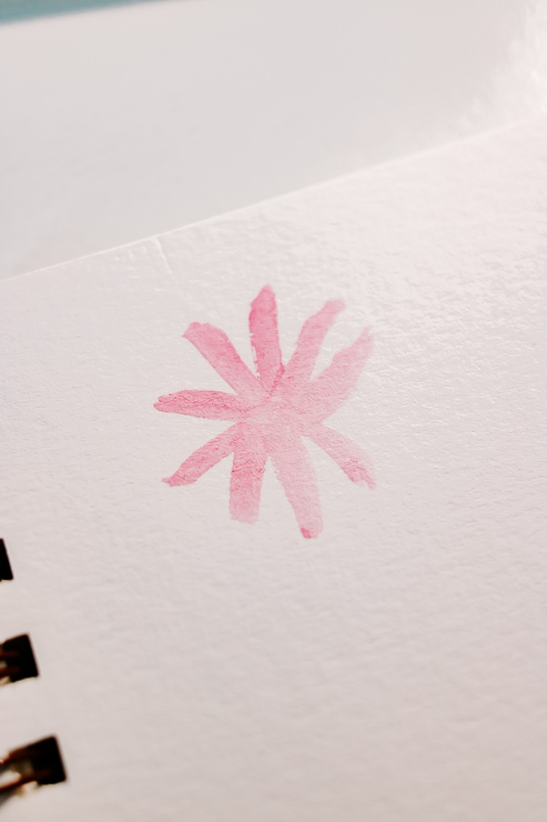 a pink watercolor flower being painted