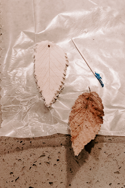 a leaf cut out of clay with a hole for hanging
