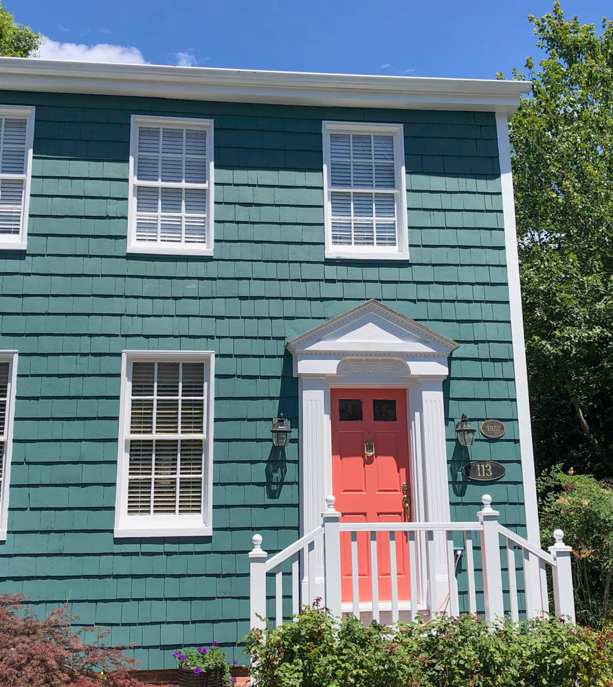 Picante by Benjamin Moore - Coral Pink from door with dark teal blue green siding and white trim