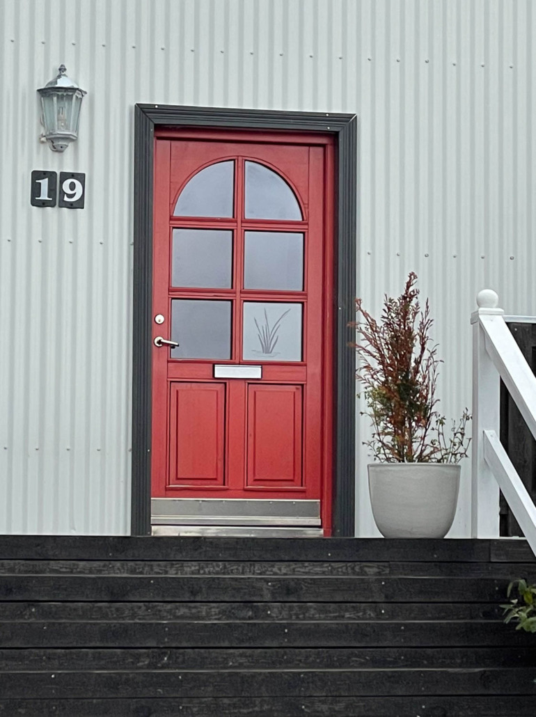 Million Dollar Red by Sherwin Williams - Iceland small town red arched half light door with gray metal siding