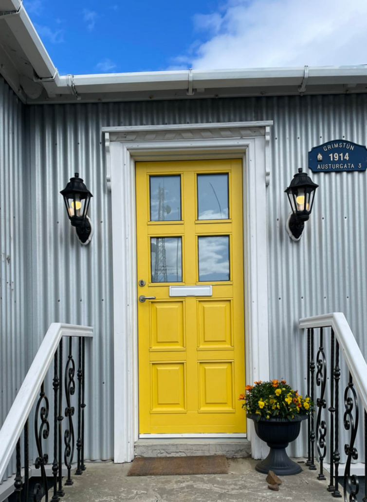 Sunshine by Benjamin Moore - Bright Yellow Door on a house with gray siding in Iceland